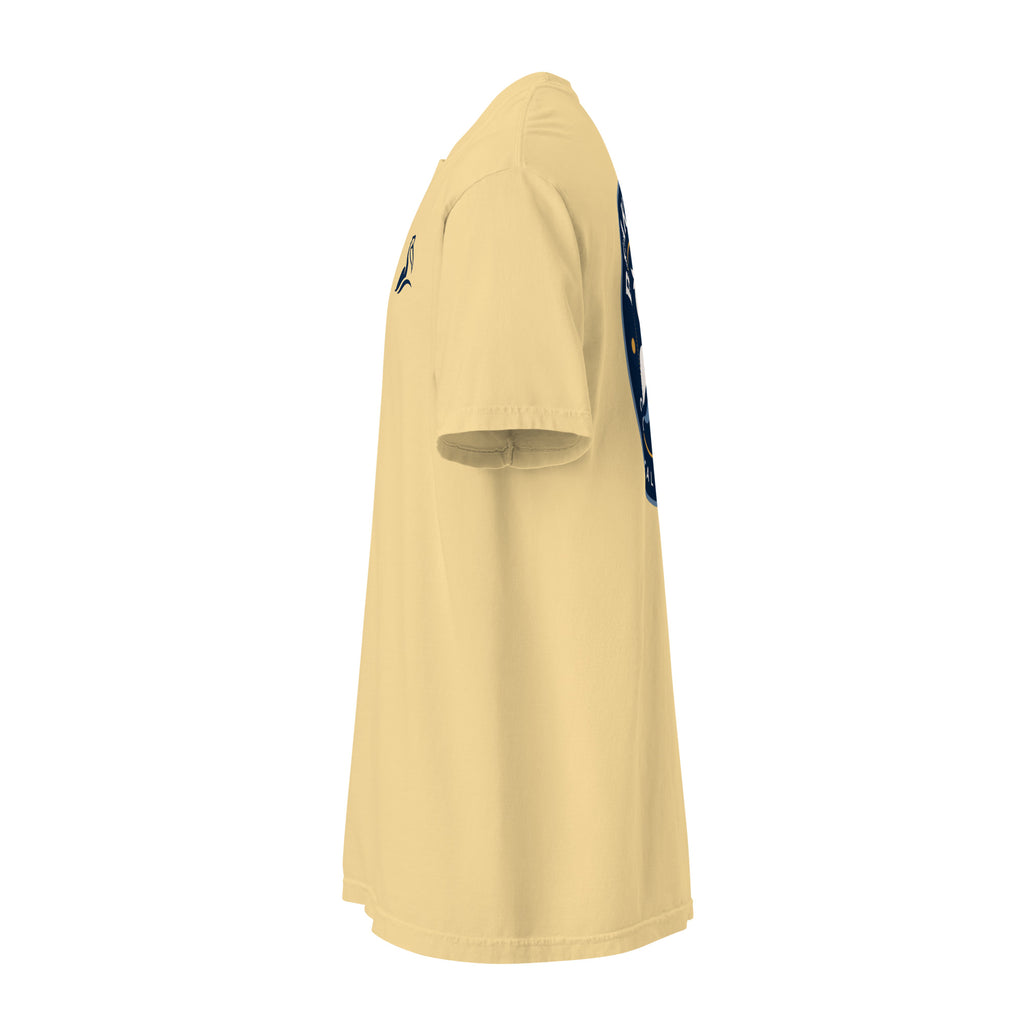 Product mockup of butter colored t-shirt with a navy blue Beak & Tide pelican logo on the left chest, side view.